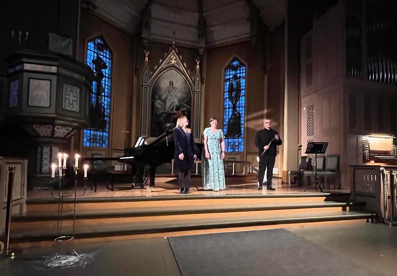 Tre musikere foran i koret med dempet belysning